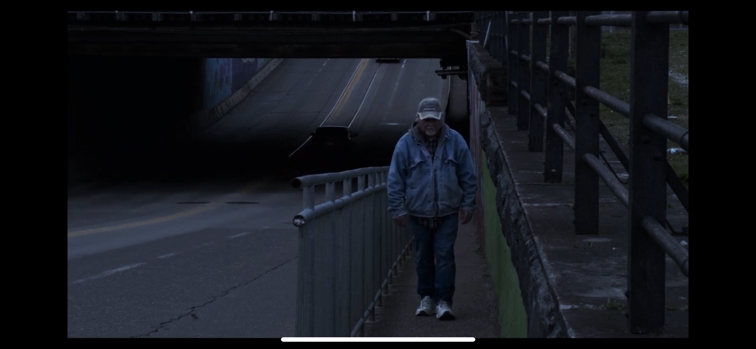 A man walks toward the coffee shop beneath an overpass in The Coffee Shop.