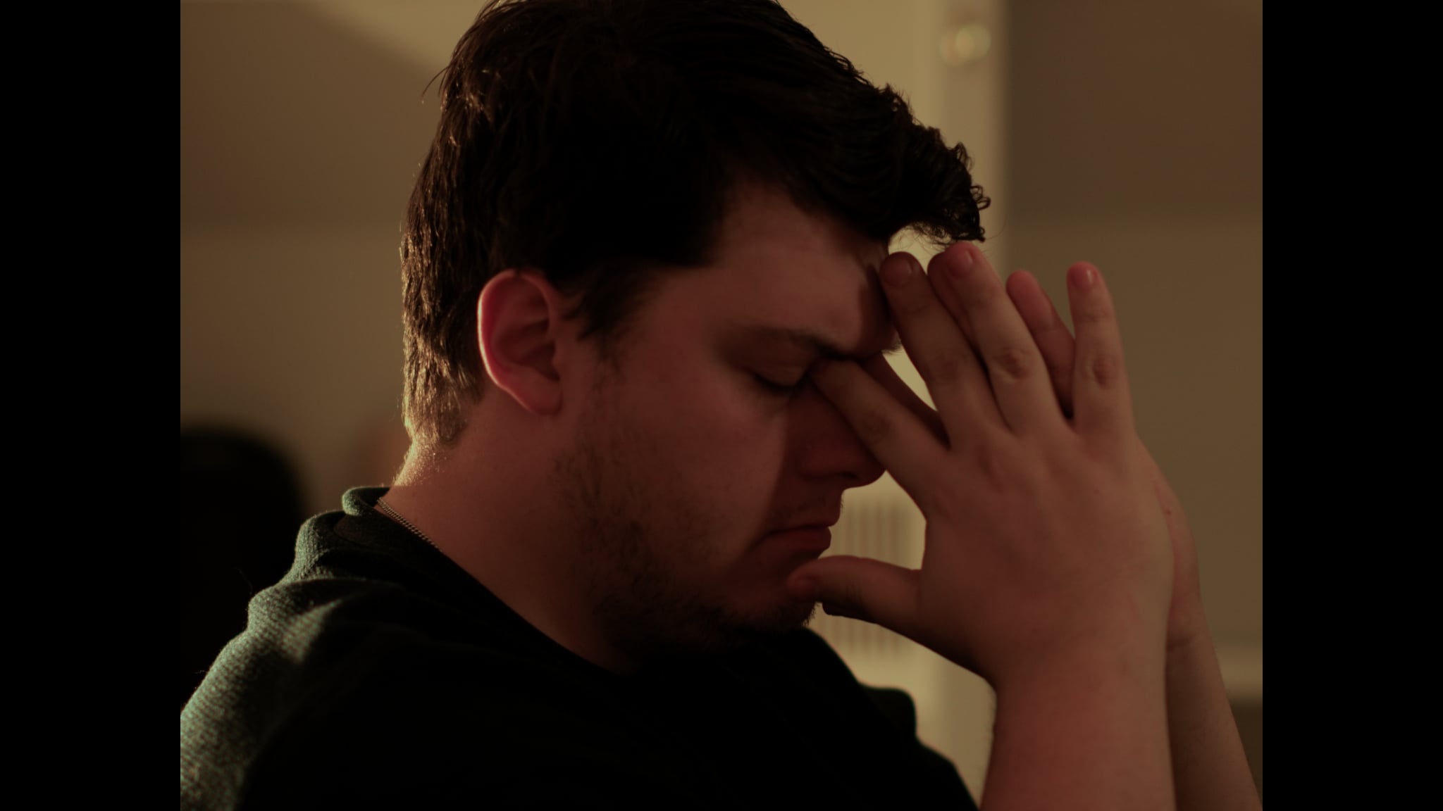 A writer holds his head in a warm, intimate frame from Echoes of a Blank Page.